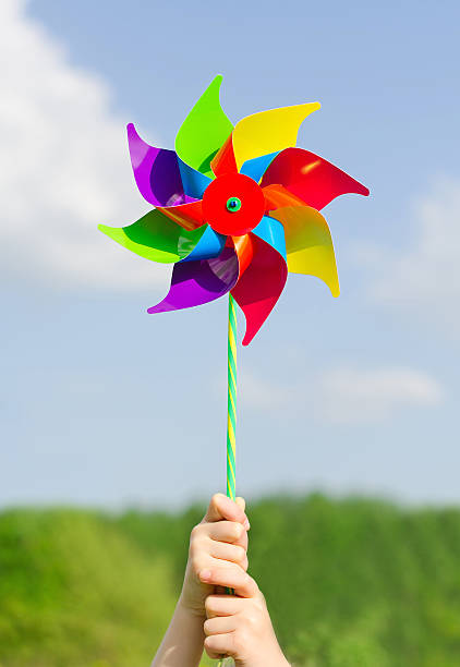 istock Child hands holding pinwheel against blue sky. 496989943