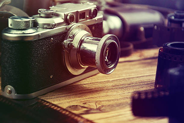 istock Old camera and blank film strip on wooden table. 496998350