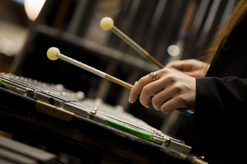 Hands girl playing a glockenspiel in dark colors closeup