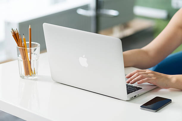 Apple MacBook Air at the desk Kiev, Ukraine - May 21, 2014: Woman sitting at the desk and typing text on a brand new Apple MacBook Air. The last version was released in April 29, 2014, designed and developed by Apple inc. apple computer stock pictures, royalty-free photos & images