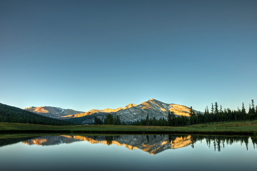 A sunrise reflection of Mammoth Peak and the Kuna Crest on a glacial pond in Dana Meadows, Yosemite National Park, California.