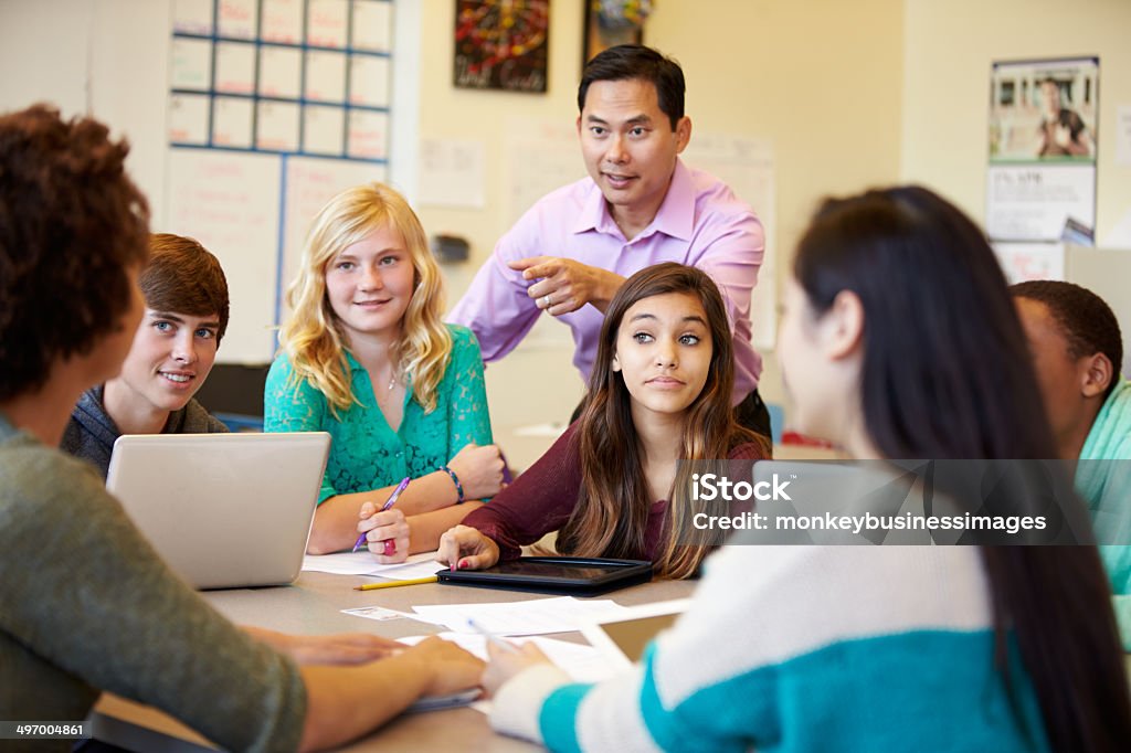 High School Students With Teacher In Class Using Laptops High School Students With Teacher In Class Using Laptops Smiling High School Stock Photo