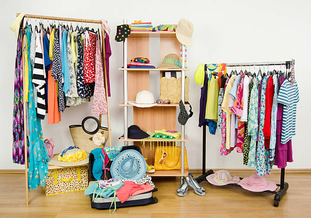 Packing the suitcase for summer vacation. Wardrobe with summer clothes nicely arranged and a full luggage. Dressing closet with colorful clothes and accessories on hangers and a shelf. sequence dress stock pictures, royalty-free photos & images