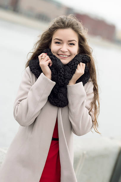 Young woman in coat onstreet smiling at the camera stock photo