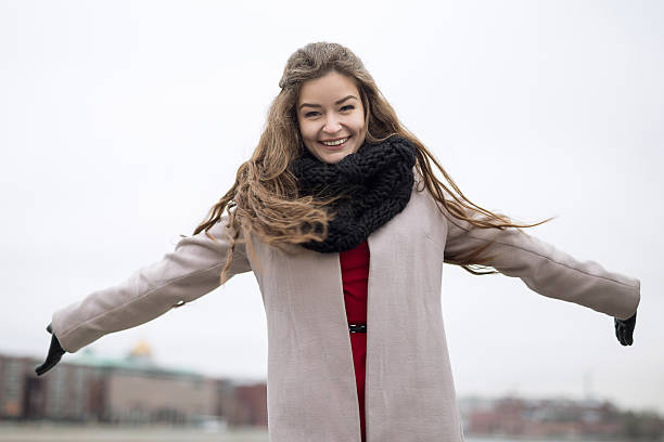 Smiling young girl in coat spread his arms. Not Isolated stock photo
