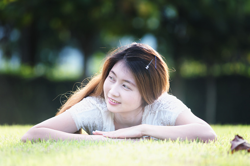 asia beautiful young woman lying on green grass in holiday