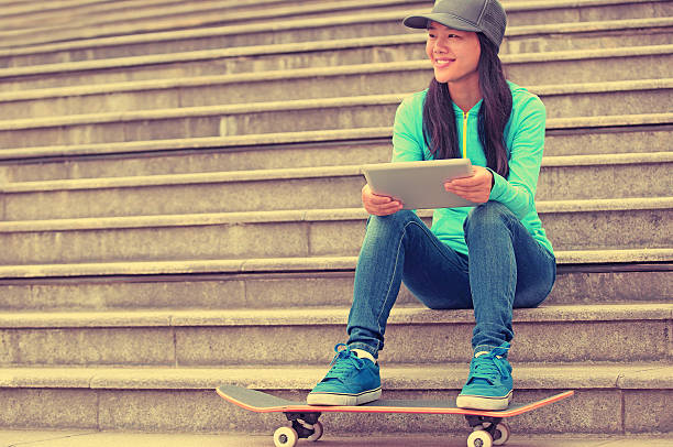 istock young woman skateboarder use her digital tablet sit on stairs 497015819