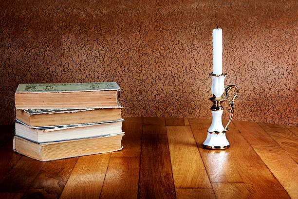 istock Old stack of books with candlestick and burning candle 497017007