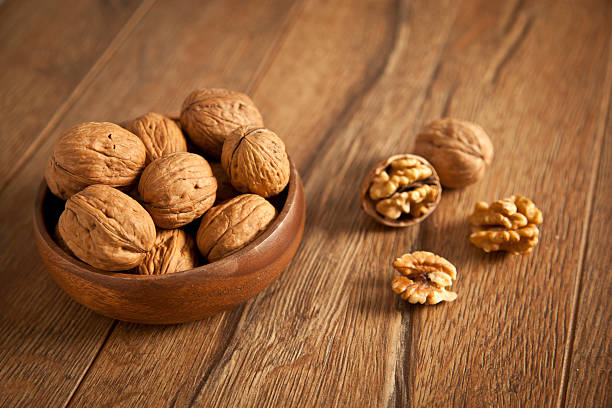 Walnut kernels and whole walnuts on rustic old wooden table stock photo