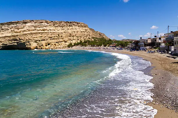 Panoramic skyline view of Matala beach , Crete. Roman era graves cut into the sinking cliffs became the lodgings for the hippies in 1960s.  Popular resort, clean beach, and clear turquoise ocean waters