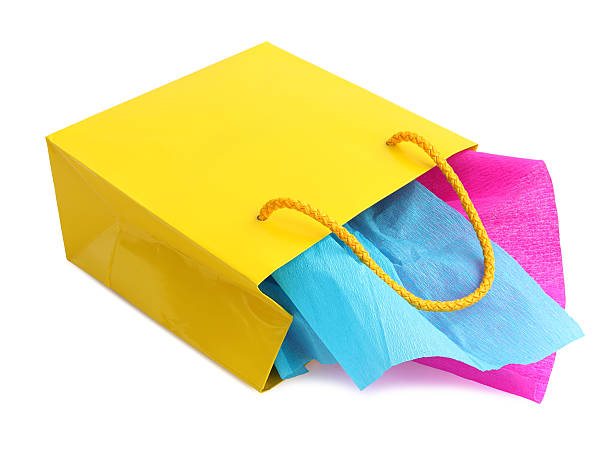 istock Yellow gift bag stuffed with pink and turquoise tissue paper 497021349