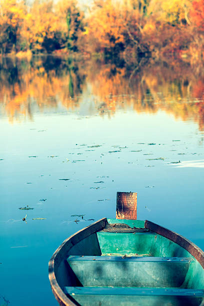Old green boat on a blue lake, fall scene
