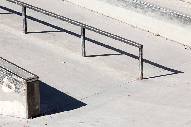Image of an empty rail at a concrete outdoor skateboard park.   There are no people in the skate park.