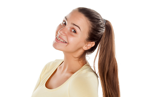 young woman with ponytail and braces posing on white background