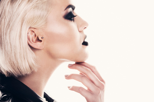 Portrait of a beautiful blonde woman with a black smokey eyes make-up and black lips, wearing black ramones leather jacket.