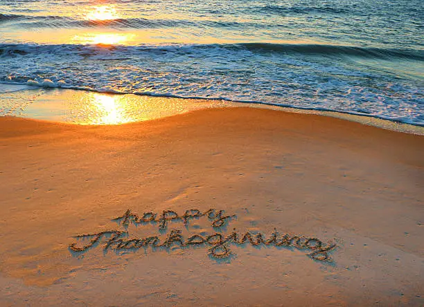 Happy Thanksgiving written in the sandy coast of Hilton Head Island during a beautiful sunrise.