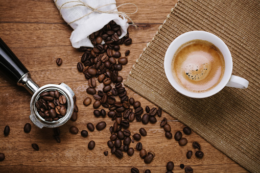 Espresso coffee overhead with spout and coffee beans on a wooden table