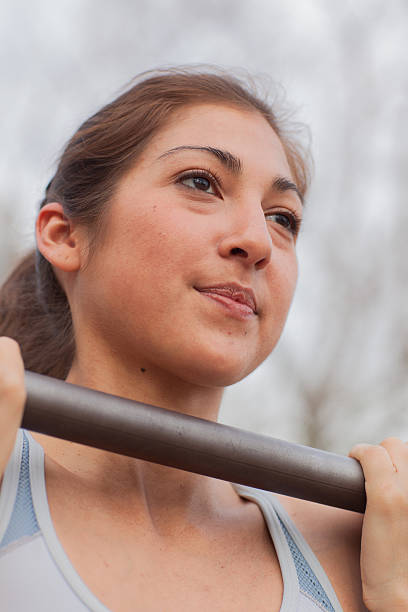 Natural light outdoor photo of athletic young Hispanic woman on outside exercise bar