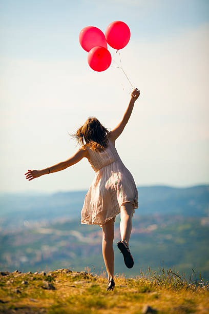 Girl with balloons on a hilltop