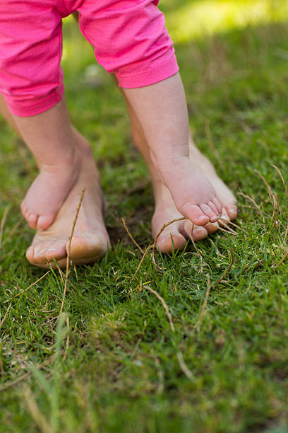 istock Little baby's legs on mother's feets at park 497037865