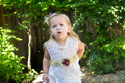 Little toddler girl in lace dress with confused and concerned expression