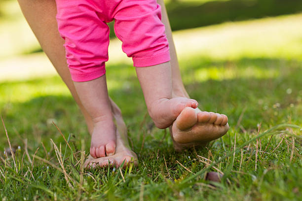 istock Little baby's legs on mother's feets at park 497040543