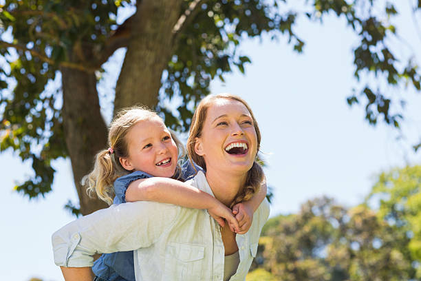 istock Mother carrying daughter on back at park 497040665