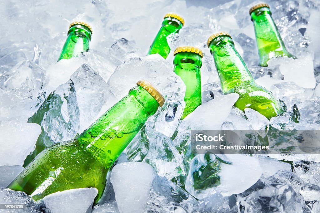 Cold beer bottles on ice Closeup of green beer bottles getting cool in ice cubes. Ice Stock Photo
