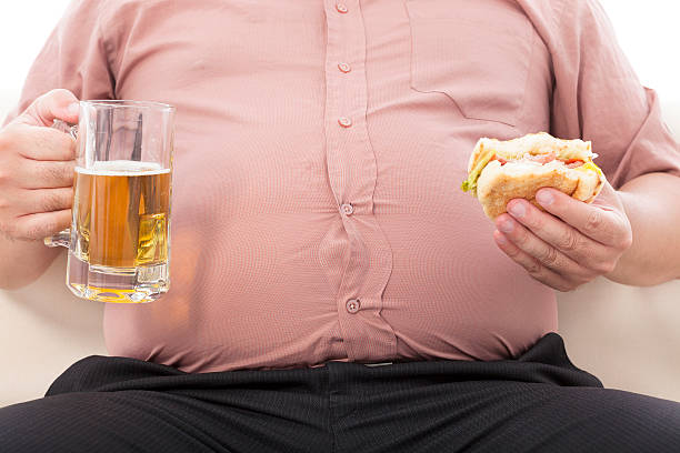 gordura negócios homem exploração caneca de cerveja e hambúrguer - dieting overweight weight scale healthcare and medicine imagens e fotografias de stock