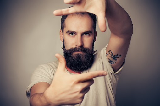 Joven Alegre fotógrafo con barba, mientras trabaja en el estudio photo