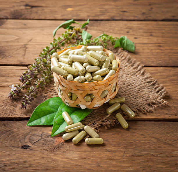 istock Herb capsule with green herbal leaf on wood 497056432