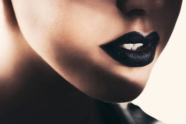 Close-up of beautiful black lips, illuminated with a selective spotlight.
