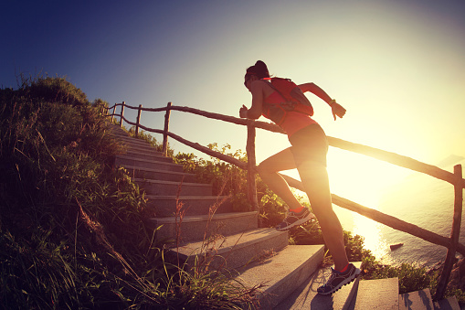 fitness woman runner trail running on seaside mountain stairs, training for cross country running.