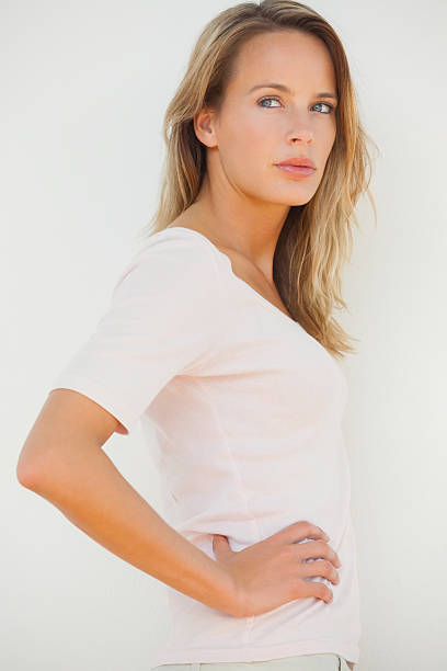Serious blonde woman posing looking away with hand on hip on white background