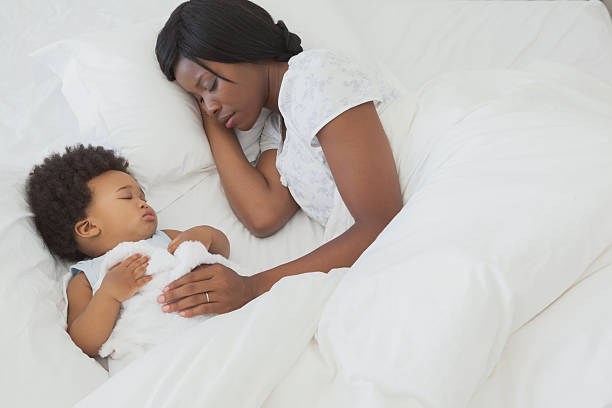 istock Cute Afro baby with mother sleeping in bed 497081589