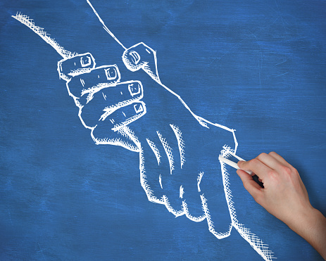 Composite image of hand drawing handshake with chalk against navy blue