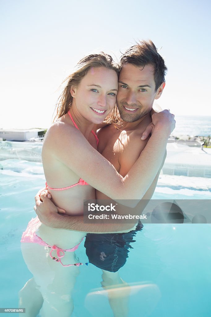 Loving young couple embracing in swimming pool Side view of a loving young couple embracing in the swimming pool 20-29 Years Stock Photo