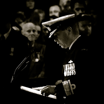 Sydney, NSW, Australia - April 25, 2012 : Rear Admiral Tim Barrett pays tribute to the fallen servicemen and women at the 2012 Sydney ANZAC Dawn Service in Martin Place, with ex-servicemen watching on solemnly in the distance