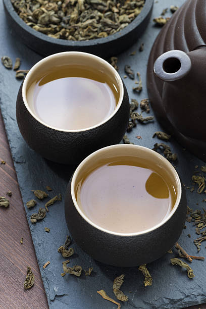 istock teapot and cups with green tea on black background 497091184