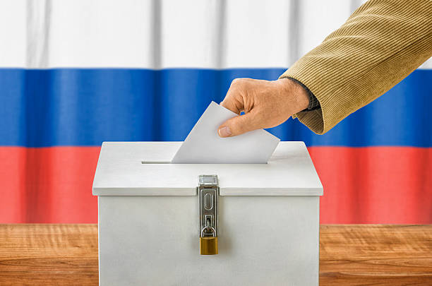 istock Man putting a ballot into a voting box - Russia 497091480