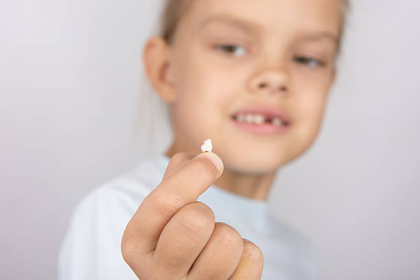 istock Six year old girl holding fallen tooth and smiling looking 497091590