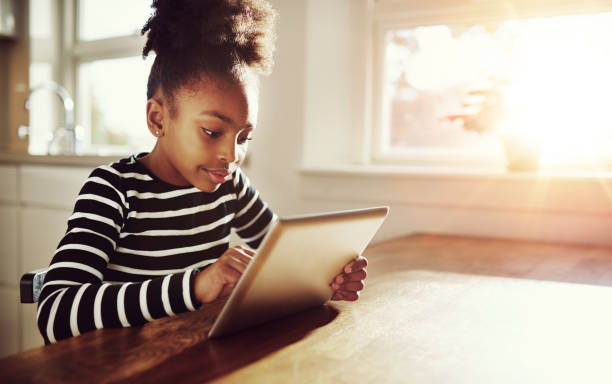 jovem negro menina navegação em um tablet-pc - hair bun hairstyle beautiful looking imagens e fotografias de stock