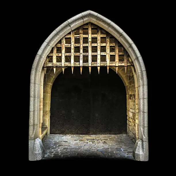 Old medieval (gothic) castle entrance, with stone wall, closed gate and spiked wooden grate, isolated on black background.