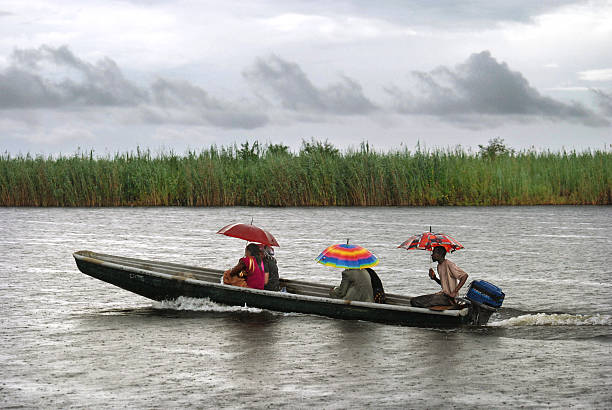 Chobe, Botswana - January 12, 2011: Local people with umbrellas travelling in a canoe during rainfall in Botswana