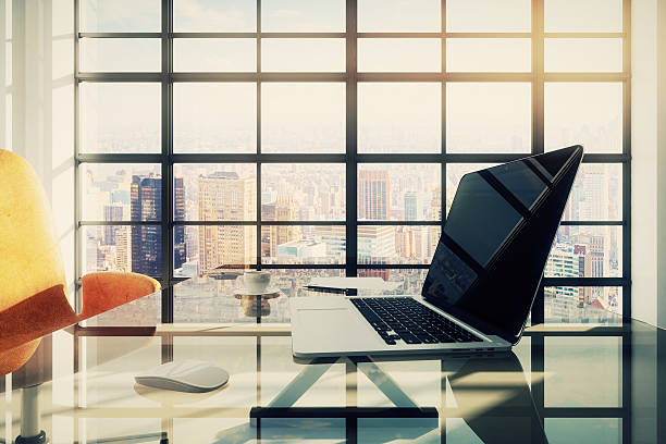 istock Laptop on glassy table in sunny office with city view 497097908