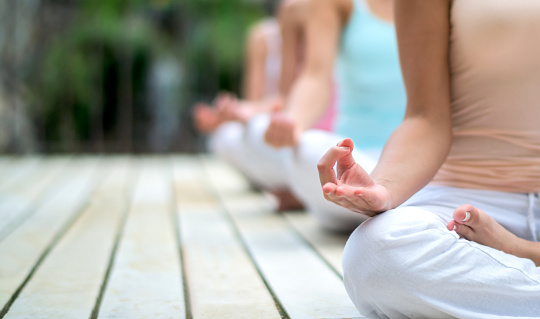 Close up on a group of people doing yoga exercises and meditating