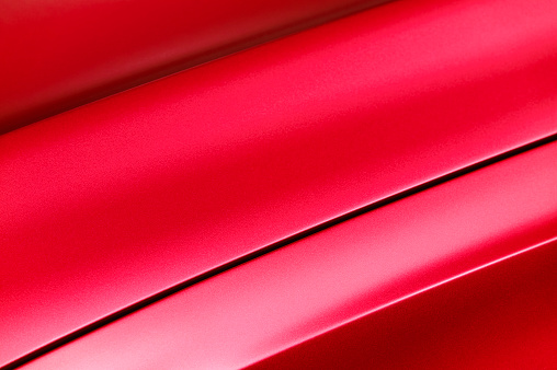 Fragment of red steel car bodywork, vehicle silver paint coating texture, selective focus, abstract