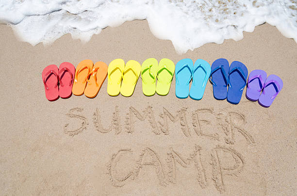 placa "summer camp" cor e chinelos de dedo na praia de areia - bech - fotografias e filmes do acervo