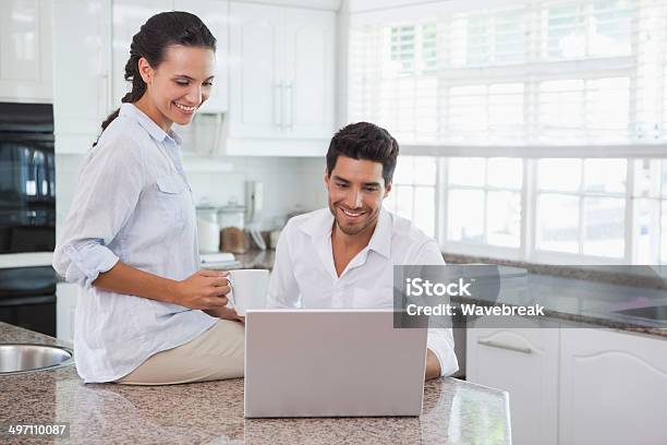 Happy Couple Using Laptop Together At The Counter Stock Photo - Download Image Now - 20-29 Years, Adult, Apartment