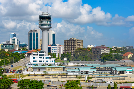 Modern glass skyscrapers stand alongside older buildings in Dar Es Salaam with maritime control tower on foreground